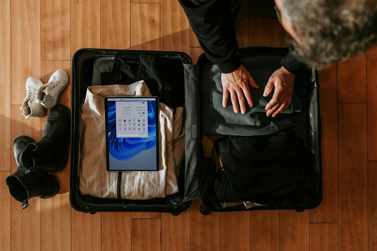 Modular packing cubes for gear arranged inside an open travel backpack — color-coded cubes hold cameras, batteries, cables, and microphones separately